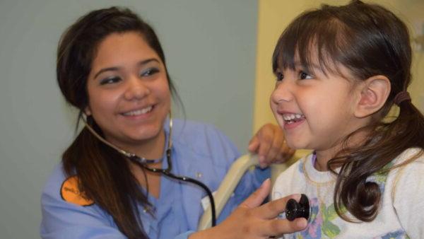 Female nursing student listening to child's heartbeat